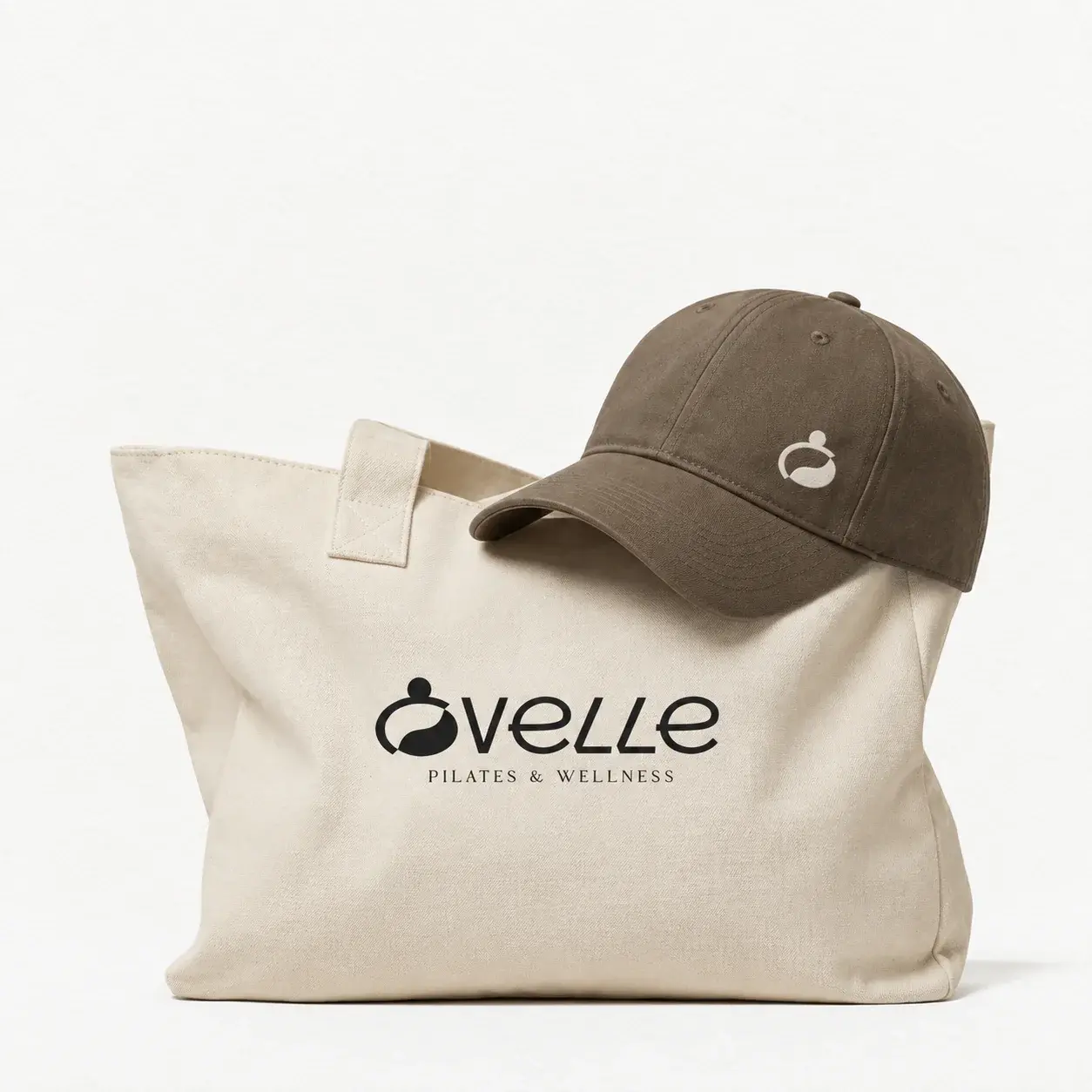 Ovelle cream tote bag and brown cap with wordmark and symbol applications.