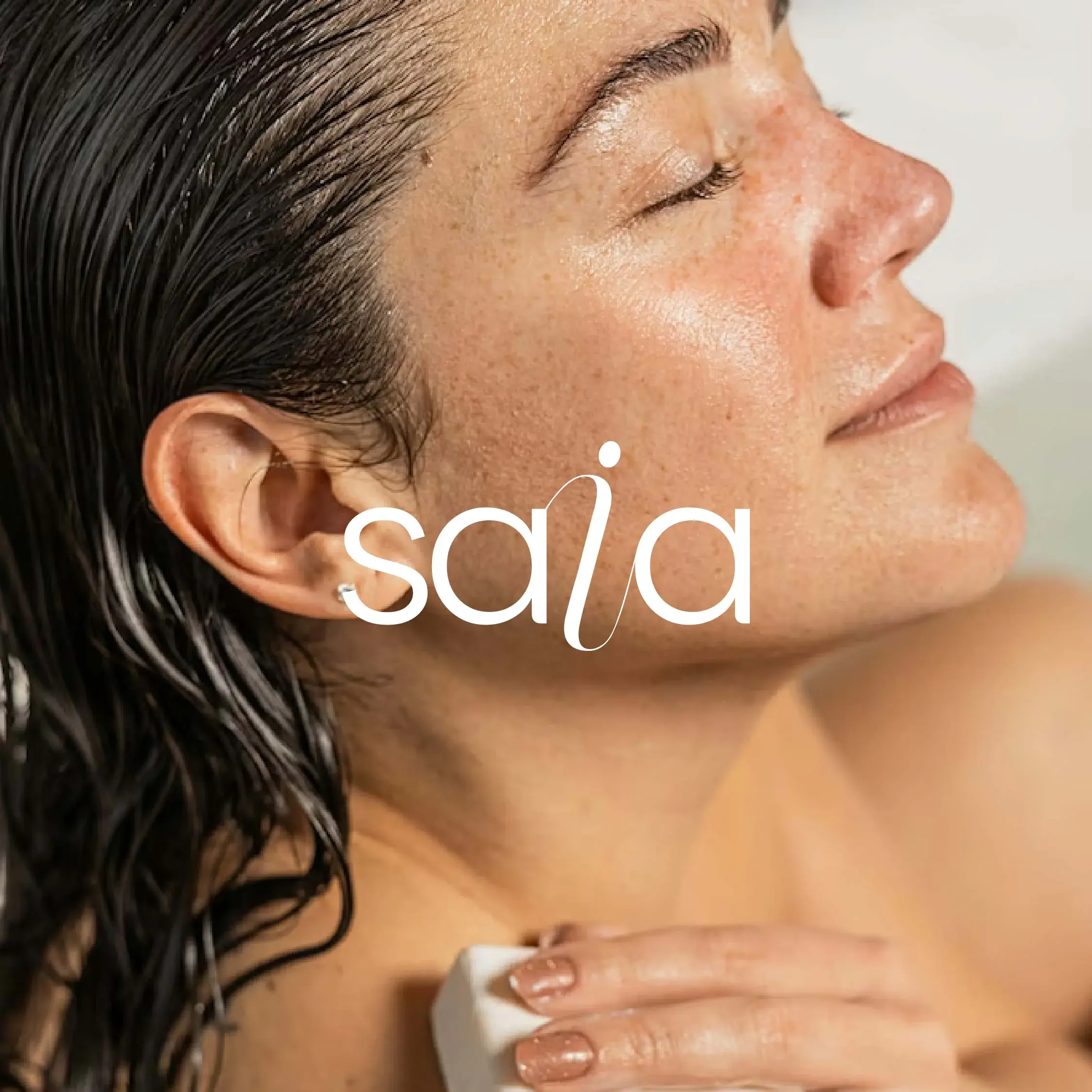 SAIA Skincare wordmark over a close-up beauty portrait with wet hair and luminous skin.