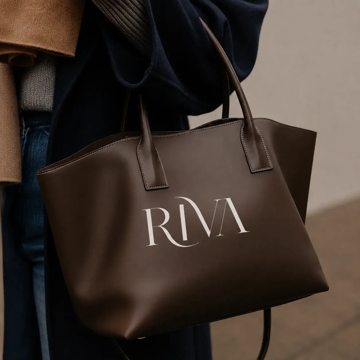 Brown RIVA handbag carried with a dark navy and camel outfit.